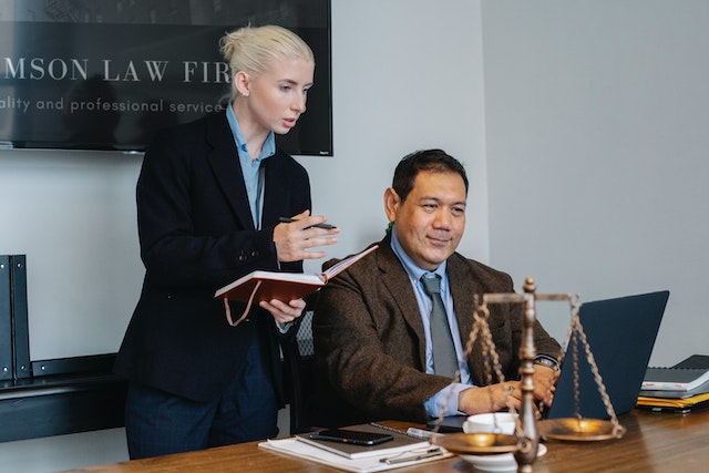 two lawyers looking at a computer with a legal balance as a decoration on the desk